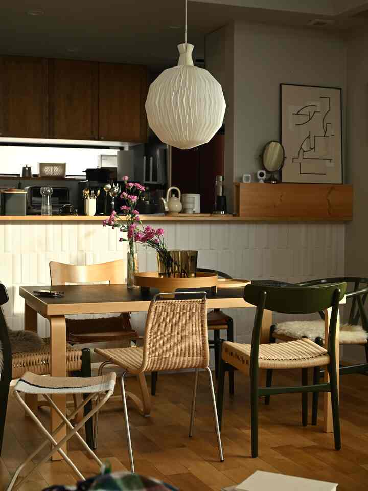 木目調と白色照明が調和する北欧スタイルのダイニングルーム、ペーパーコードチェアと花瓶が配置された温かみのある空間