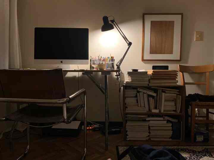 Brown and black toned home office featuring desk, office chair, and stacked books creating a cozy setting