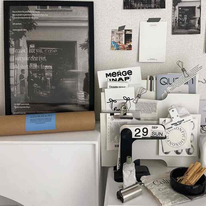 白を基調としたホームオフィスのデスク、ポスターが配置された落ち着いた雰囲気の空間