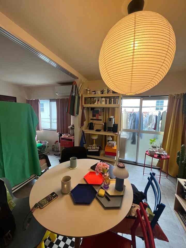 Cafe style dining room with white table and colorful chairs, featuring window lighting and storage shelves in a cozy space