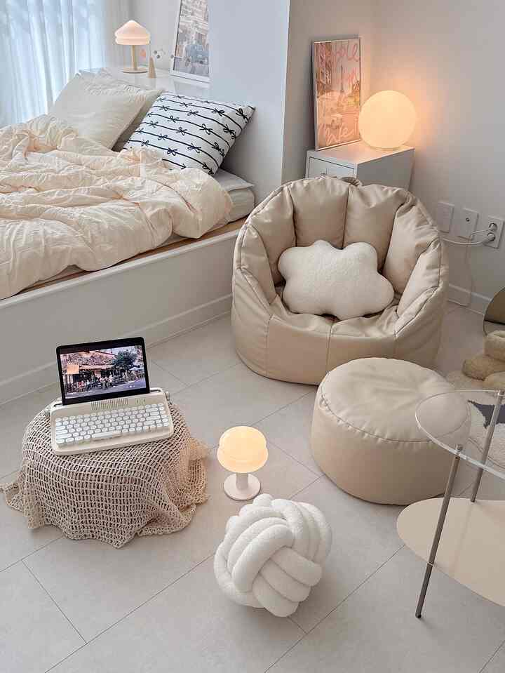 ベージュと白を基調とした寝室、ベージュのビーズクッションとスツール、ノートパソコンやクッションが配置されたシンプルで自然な雰囲気のインテリア