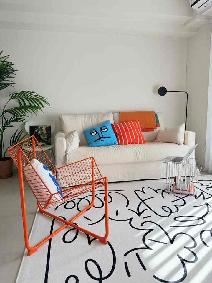Bright white living room featuring an orange metal chair and white sofa with a modern and clean interior design