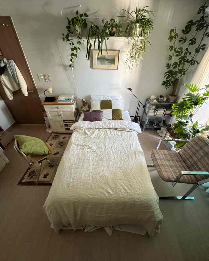 ナチュラルな色調の寝室、壁棚に植物と枕が配置された雰囲気のある空間