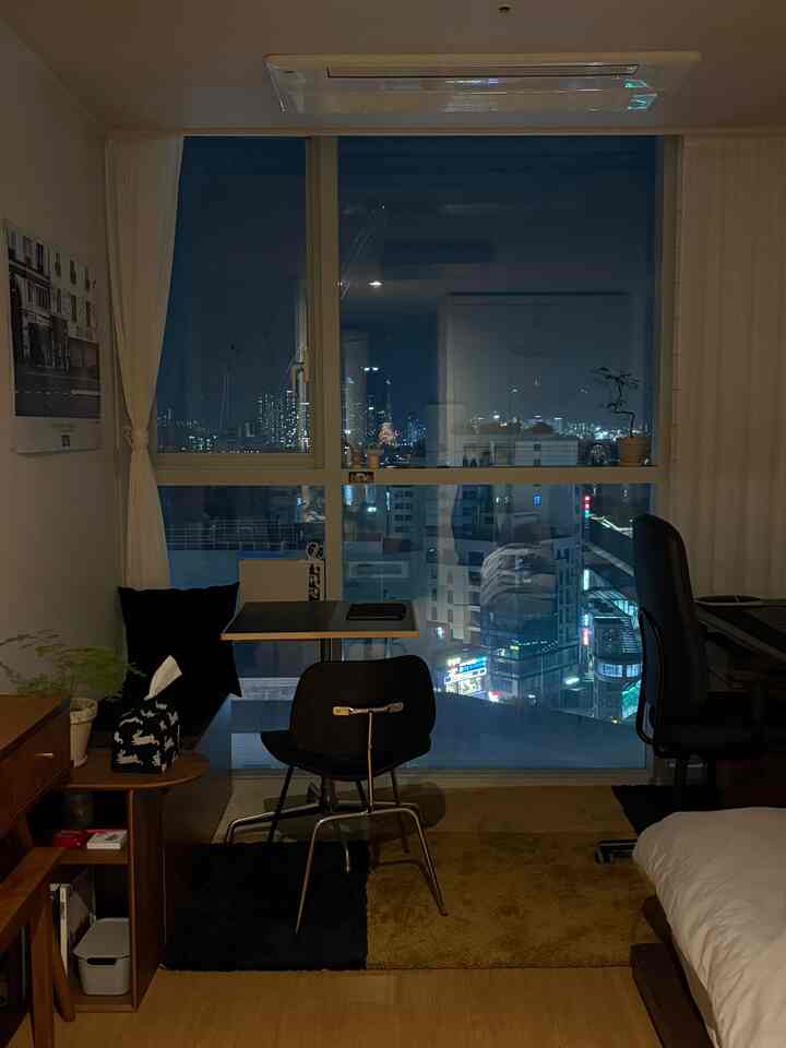 夜の落ち着いた雰囲気の7坪ワンルーム、広い窓とモダンなデスクやベッドが配置された自然な色調の空間