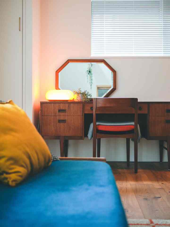 Bright and clean living room featuring a deep blue sofa and warm wood-tone vanity