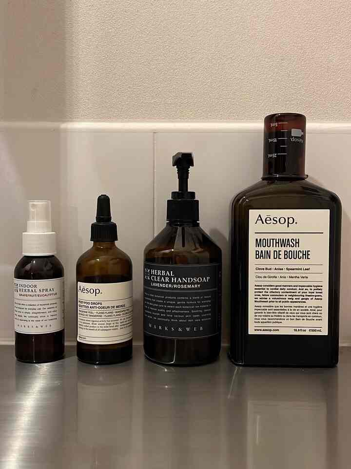 ナチュラルブラウンの色調のバスルームカウンターにアロマや洗浄製品が整然と並んだ清潔感のある空間