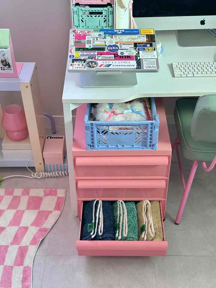 ピンクとホワイトの色調が印象的なコンパクトなホームオフィス、デスクと引き出しに整頓されたタオルが配された雰囲気のあるインテリア