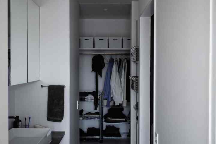 White-toned compact walk-in closet with storage shelves in a modern laundry space