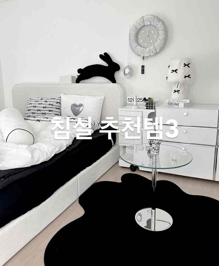 モノトーンの黒白寝室、不整形のラグとガラスのサイドテーブルが配置されたシンプルでモダンなインテリア