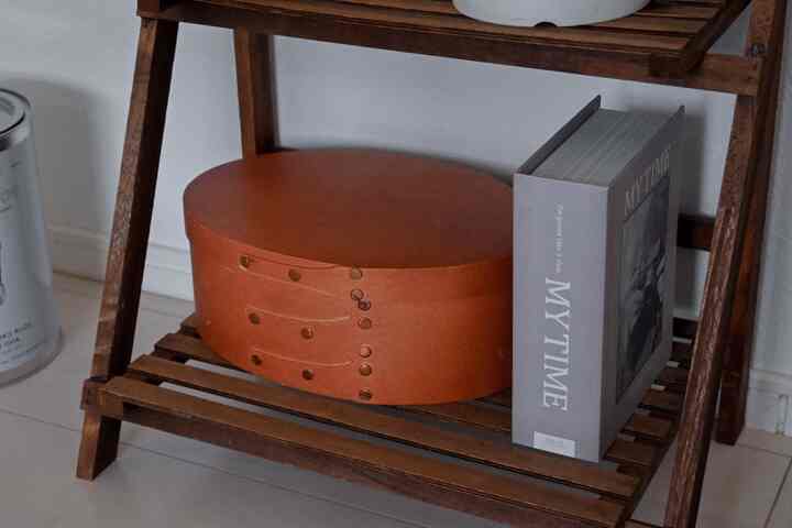 Natural wood tone compact shelf with an oval box and a book, creating a simple and cozy atmosphere