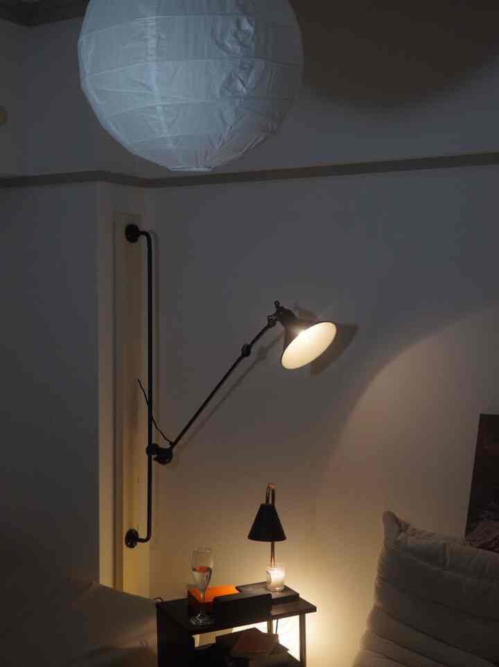 Black and white toned living space with adjustable wall-mounted lamp and a side table, creating a cozy atmosphere