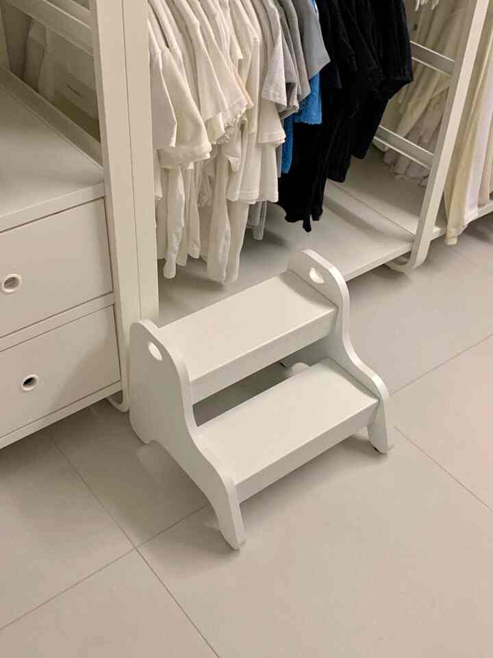 ホワイトトーンのウォークインクローゼット、ホワイトのスツールとクローゼットが配置された整然とした空間