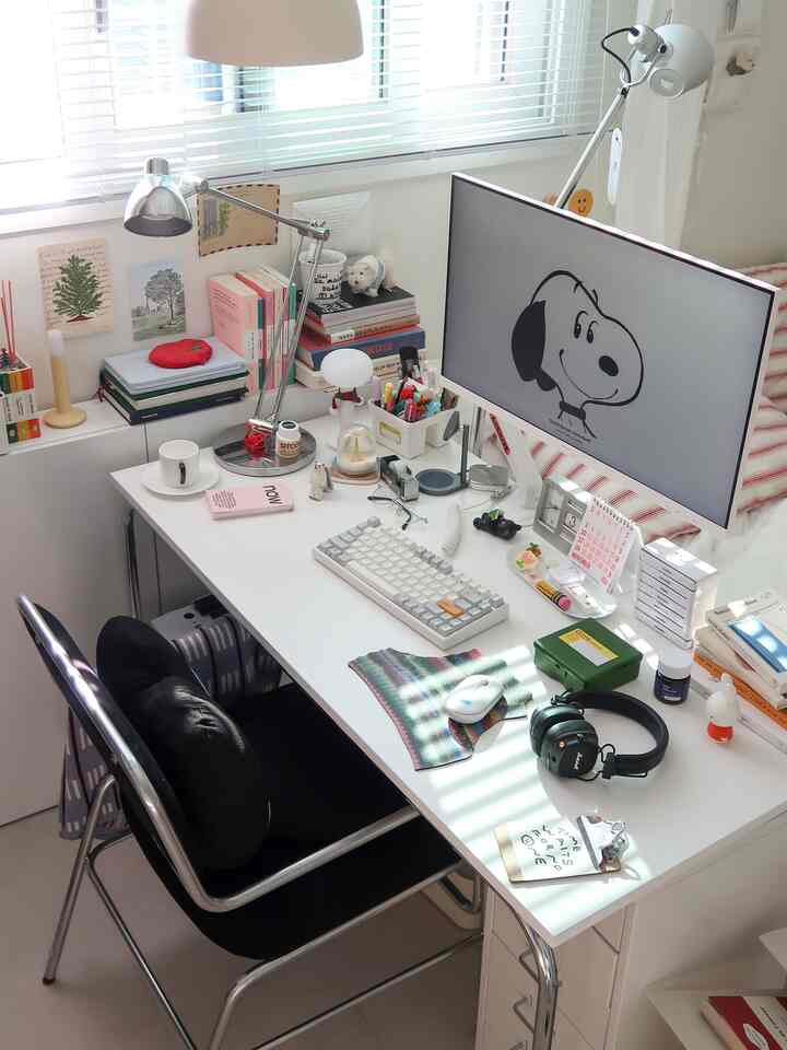 白を基調としたコンパクトなホームオフィス、モニターと文房具が整然と配置された雰囲気のあるインテリア
