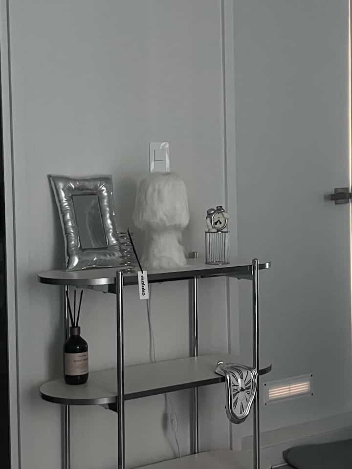 Mid-Century Modern style rack in white and silver tones featuring clocks, diffuser, and lamp in a clean interior setting