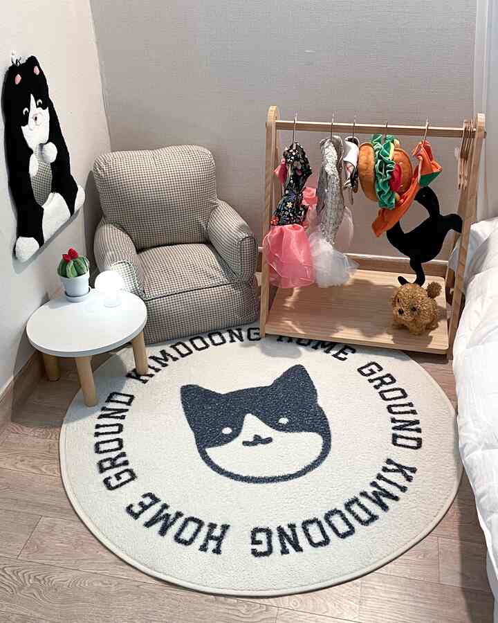 ホワイトとナチュラルカラーの猫部屋、かわいい猫柄ラグと小さなチェック柄のソファ、猫用コスチュームラックが配置された温かみのあるインテリア
