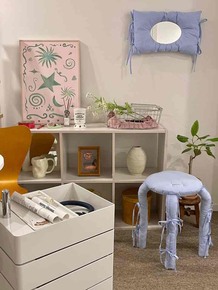 White and beige toned living room featuring wood-tone chair and bookshelf with a cozy, minimal atmosphere