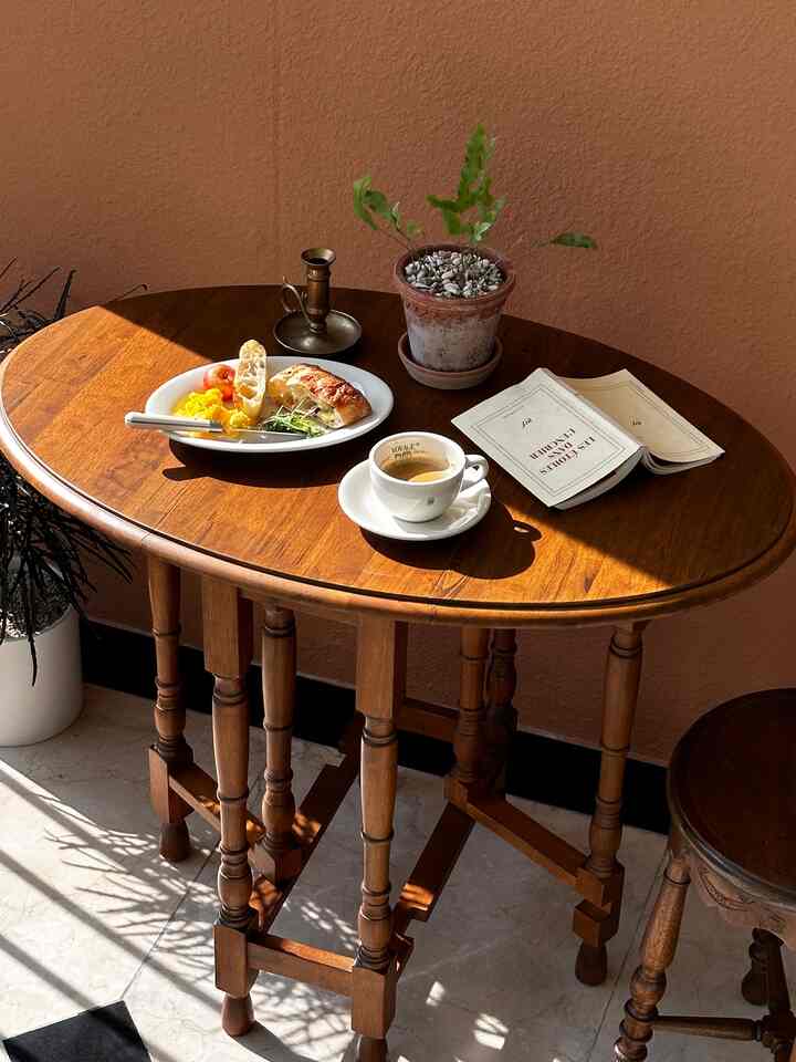 Warm wood tone vintage dining table with bread and coffee on it, creating a cozy cafe style atmosphere