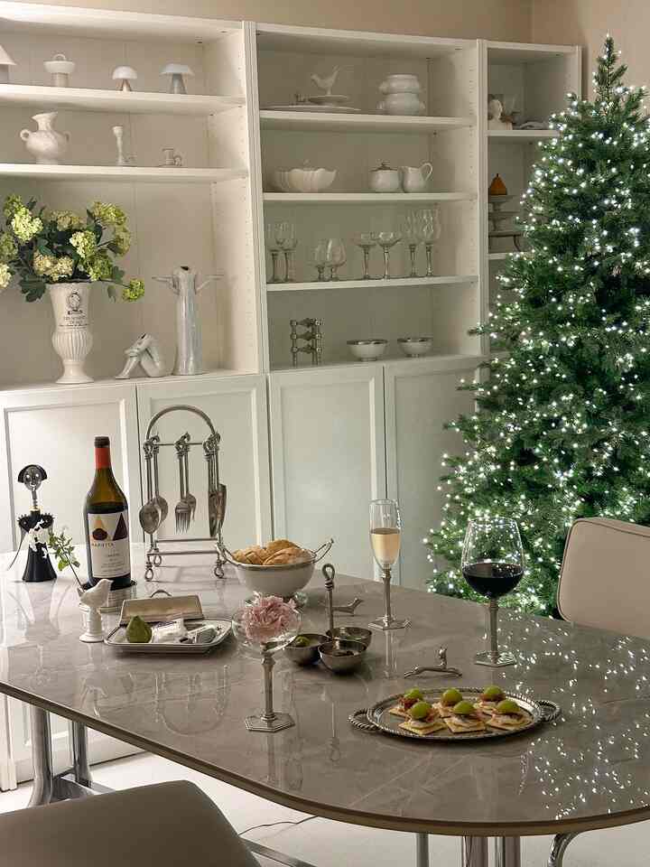 White and gray toned dining room featuring a Christmas tree and wine glasses on a home party table, creating a cozy atmosphere