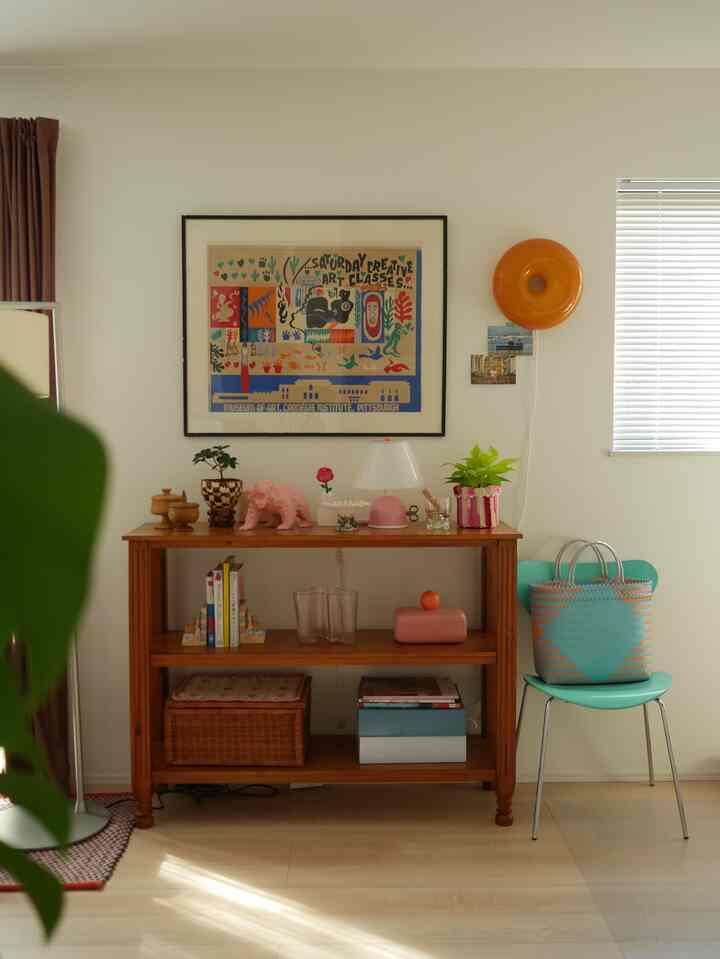 Natural wood tones with pink and navy accents in a living room featuring retro vintage wall art and a decorative shelf