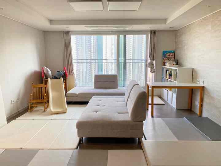 落ち着いたベージュの色調のリビング、子供の遊具とデスクが配置された整頓された空間