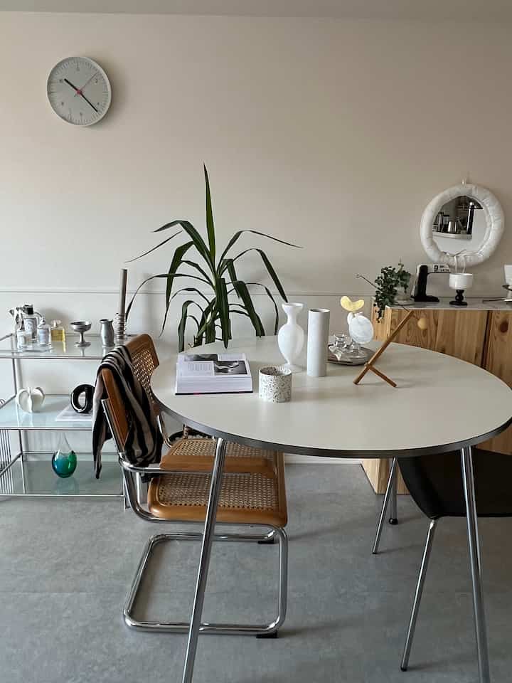 ホワイトと木目調が調和したダイニング、ラウンドテーブルとサイドテーブルが配置されたモダンで清潔感のある空間