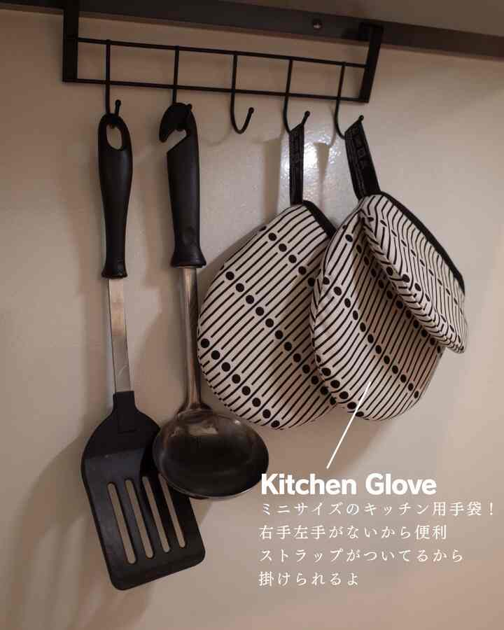 黒の調理器具とミラーブラックキッチン手袋セットが壁のフックに掛けられたキッチンスペース
