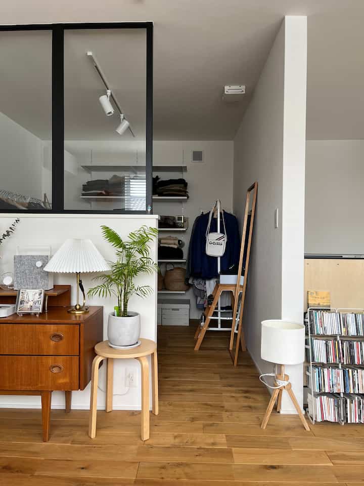 Natural wood-tone floor and vintage furniture blend in a tidy living room space, featuring storage and lighting elements