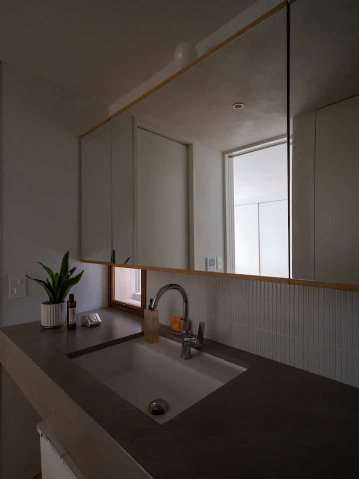 White and gray toned bathroom featuring a sink and three-sided mirror with a modern interior including a visible cat litter box