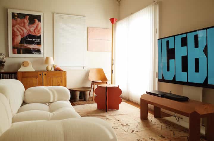 Bright white and beige toned living room featuring a plush cushioned sofa and uniquely designed coffee table creating a cozy atmosphere