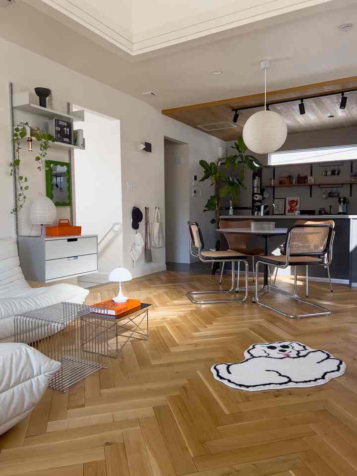 Bright white and wood tone living room featuring a sofa and wooden dining chairs with a natural atmosphere