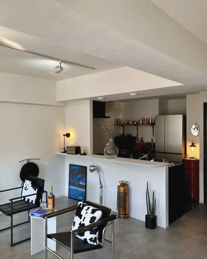 白い壁と黒い家具が配置されたインダストリアルとミッドセンチュリーモダンスタイルのリビングキッチン空間