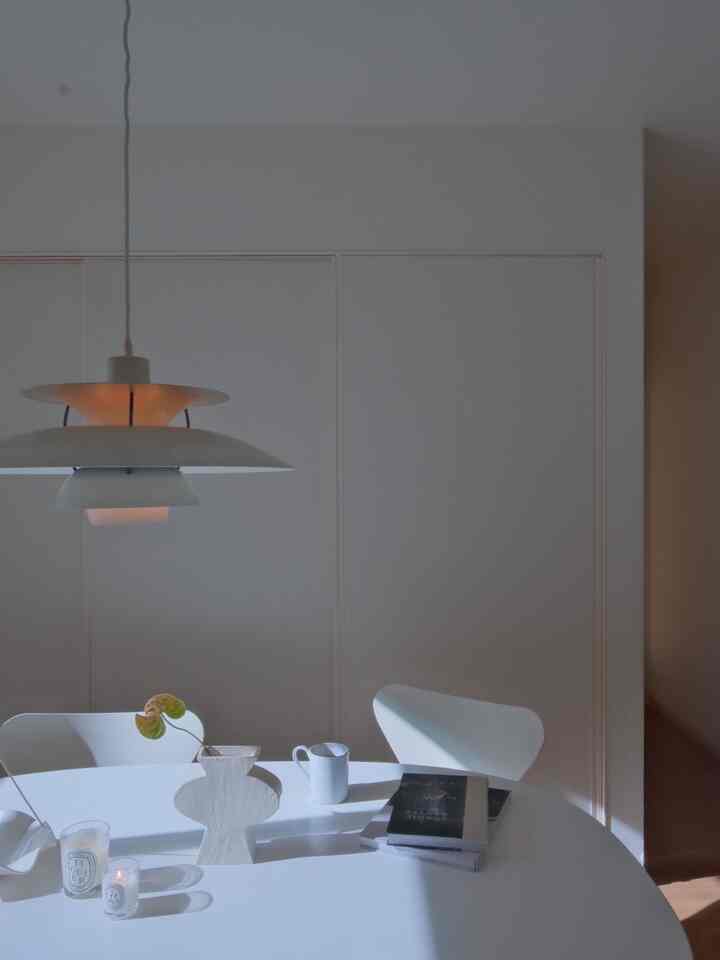 白を基調としたダイニングルーム、スーパー楕円テーブルとセブンチェア、PH5ペンダントライトが配置されたシンプルで落ち着いた空間