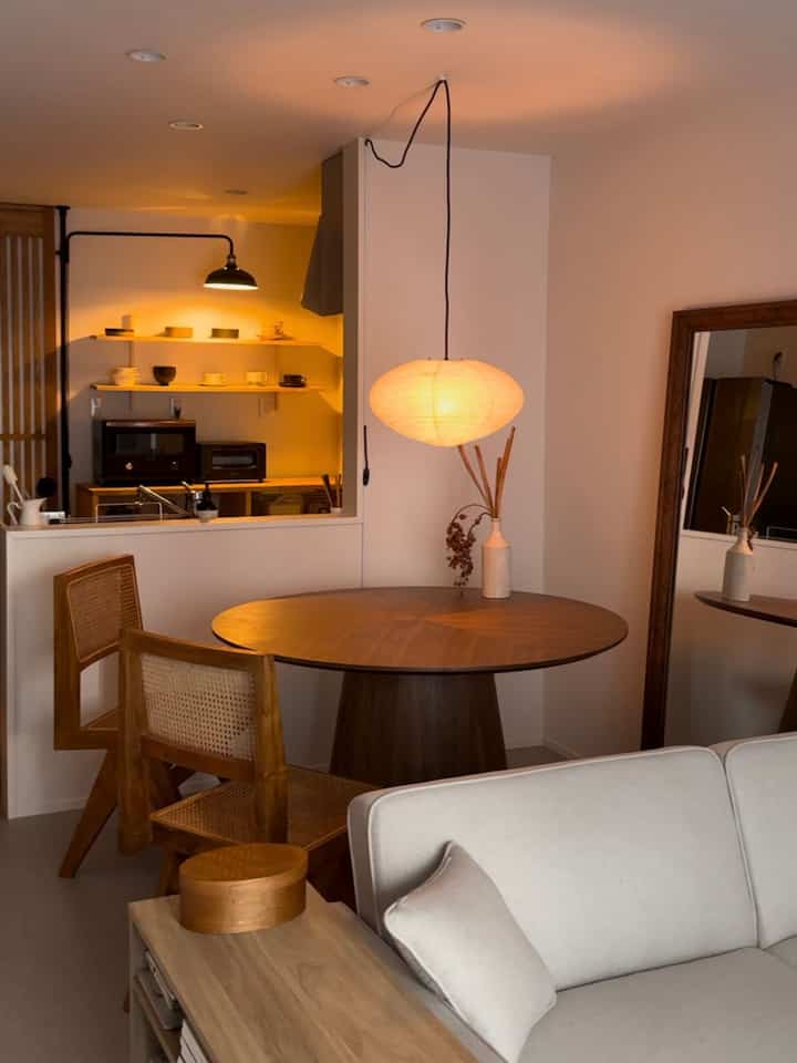 ベージュとナチュラルトーンのダイニングルーム、丸い木製テーブルとペンダントライトが温かみのある雰囲気を演出する和モダンなインテリア