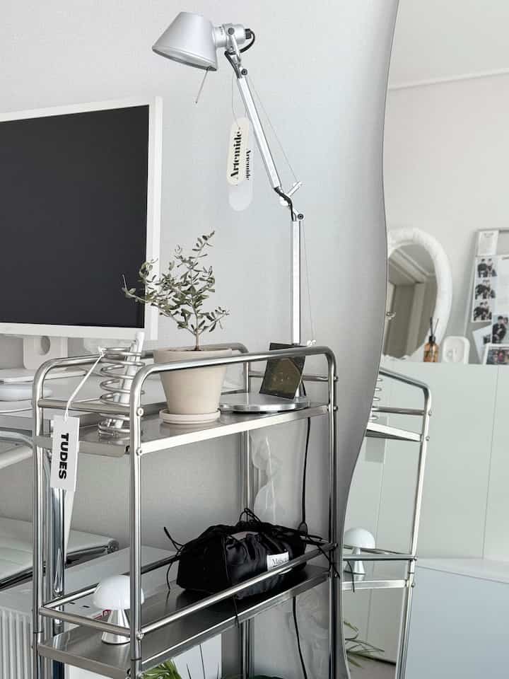 シルバーとホワイトのトーンのリビング、クロム製トロリーとテーブルランプが配置されたミニマルで落ち着いた雰囲気のインテリア