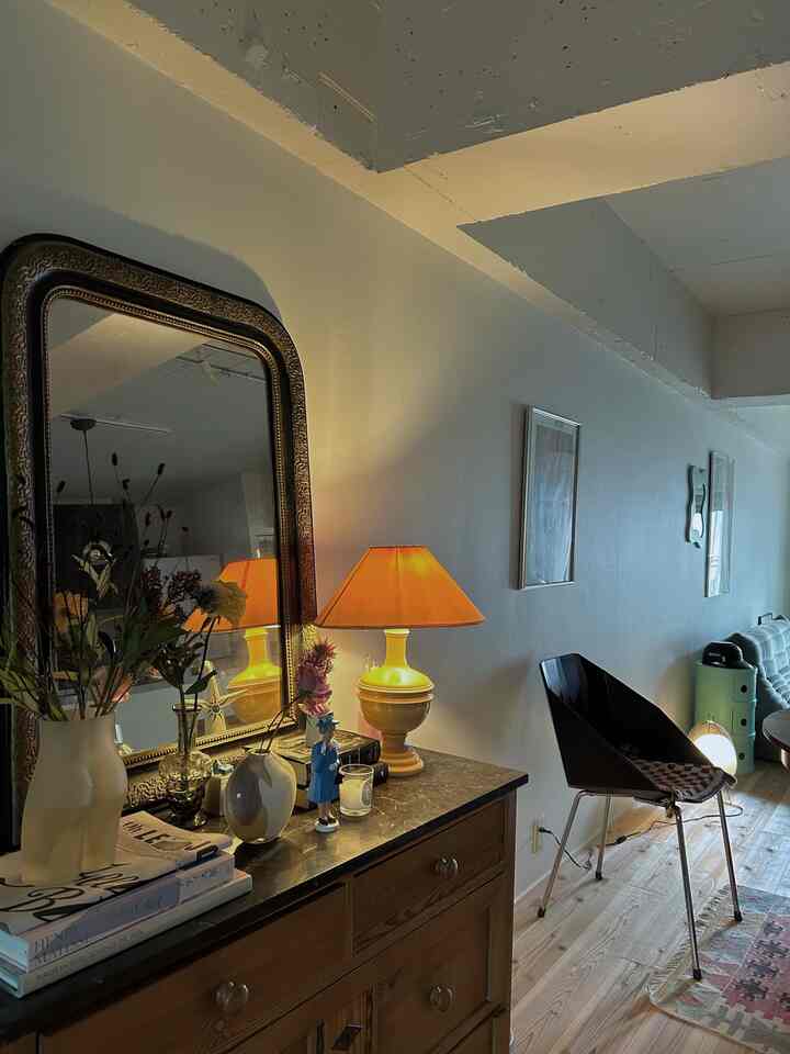 暖かいオレンジ色の照明があるヴィンテージ風リビング、木製チェストと花の飾りが配置された空間