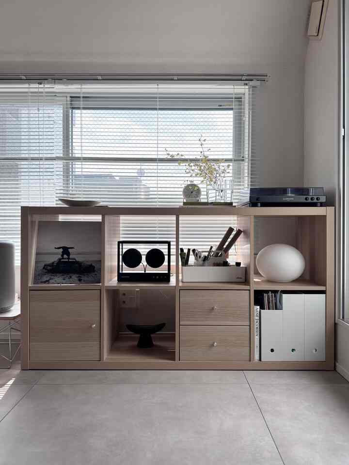 明るいナチュラルウッド調と白が調和した北欧スタイルのリビングの一角、IKEAの本棚とシンプルな小物が整然とした雰囲気を演出