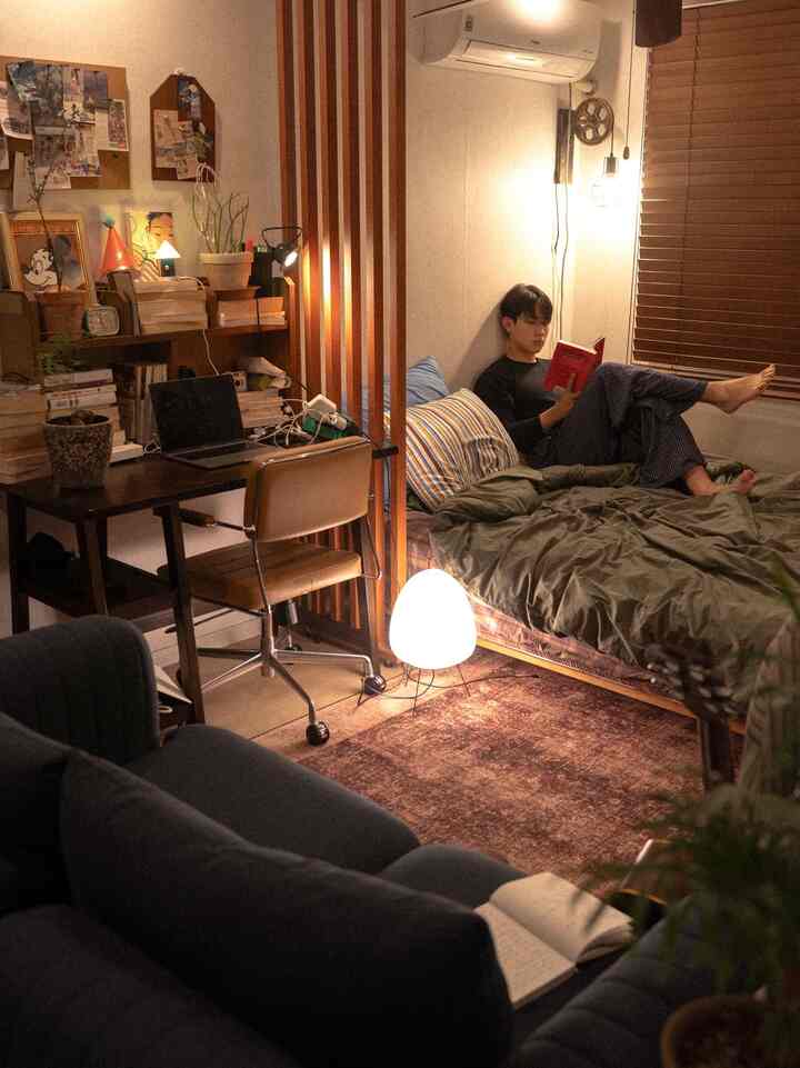 ナチュラルな色調のワンルーム寝室兼リビング、木製の間仕切りとデスクが配置された雰囲気のあるインテリア