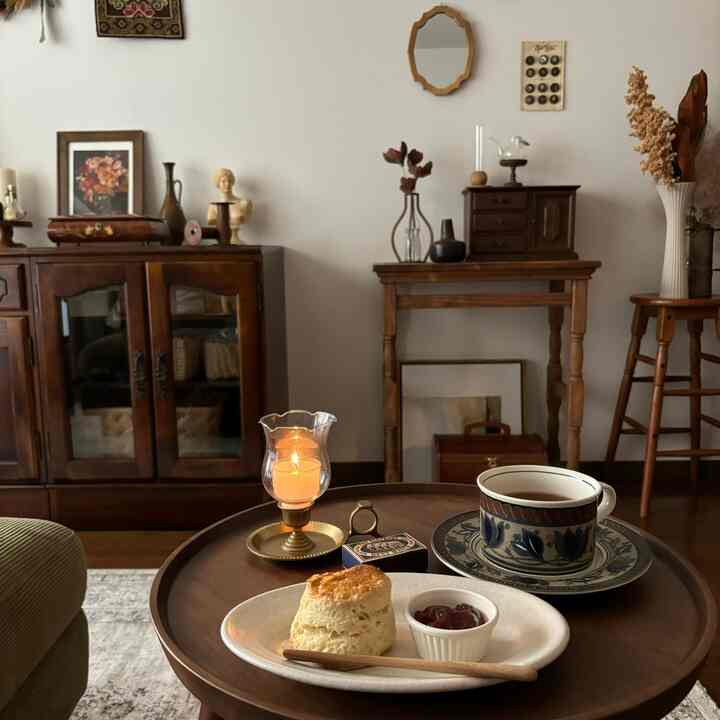 Warm brown wood-toned vintage living room featuring cozy home cafe elements with a tea cup and scone on a round wooden table