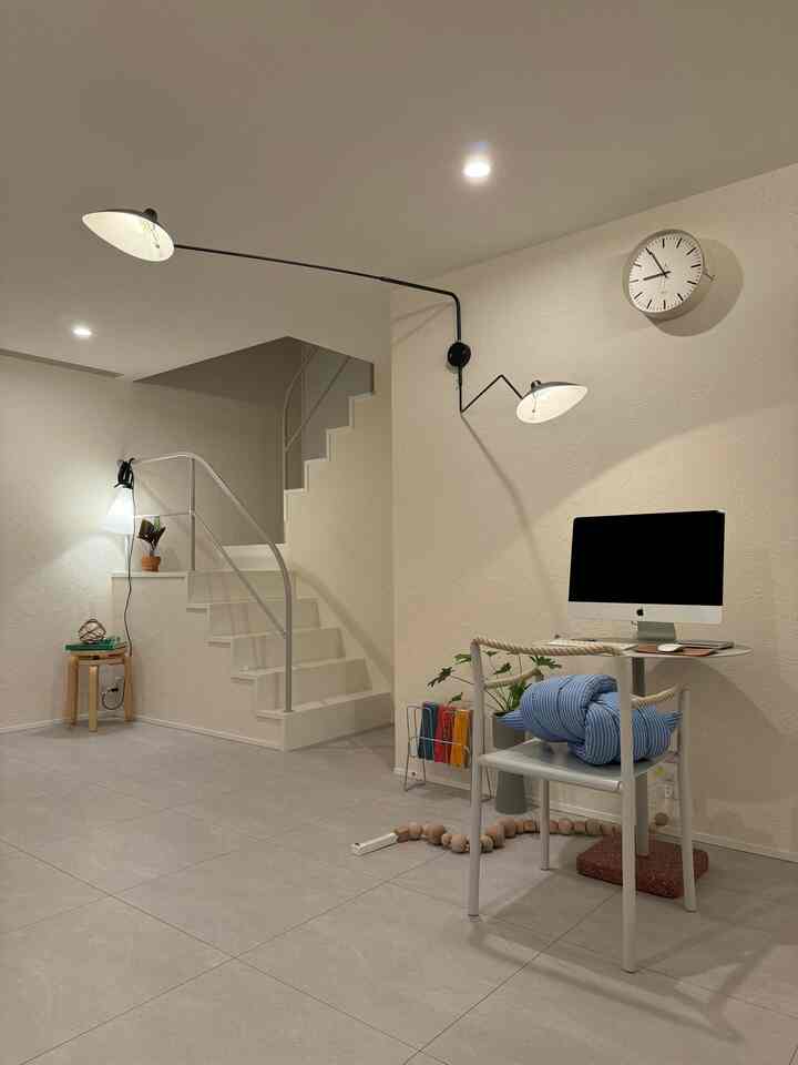 Soft beige walls and light gray tiled floor room featuring minimal stairs and a chair holding a computer in a simple modern home office interior