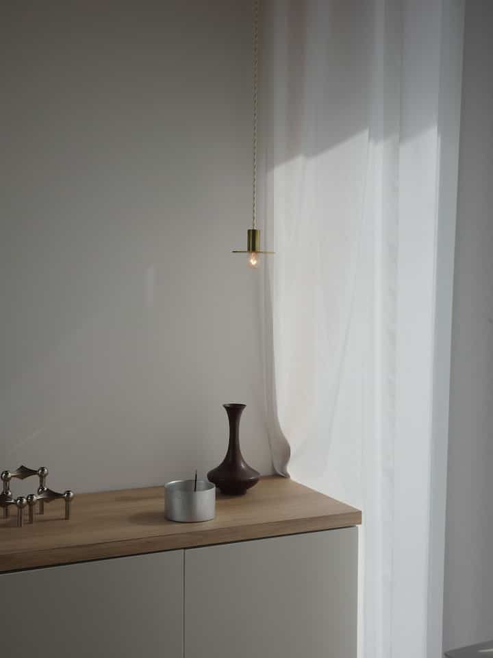 白とベージュの色調の玄関、シンプルなコンソールテーブルの上に香炉と花瓶が置かれた落ち着いた雰囲気のあるインテリア