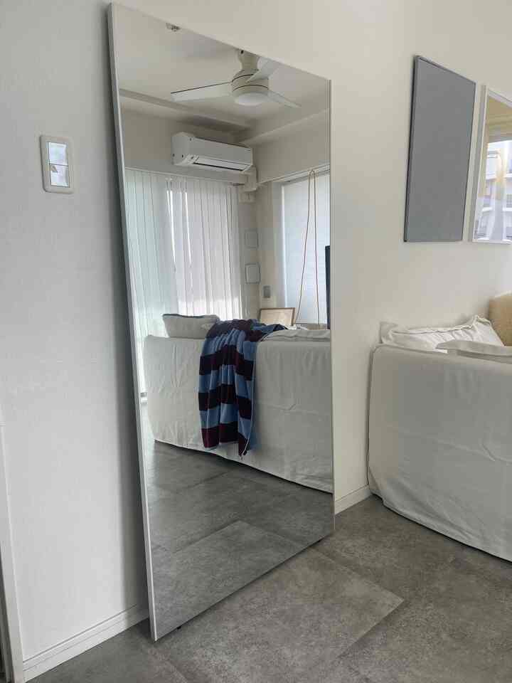 白とナチュラルな色調のリビング、大きな鏡と白いソファが配置され、明るく広々とした雰囲気のあるインテリア