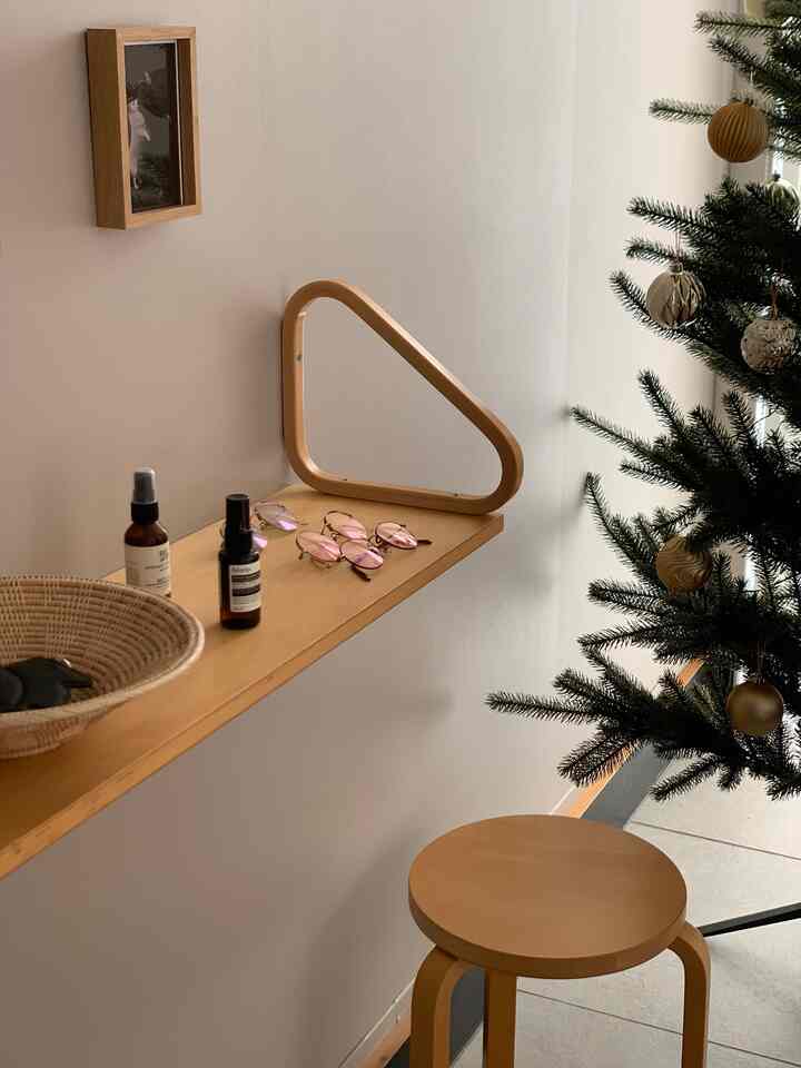 Natural wood tone and white-walled entrance featuring Christmas tree, stool, and shelf with a warm atmosphere