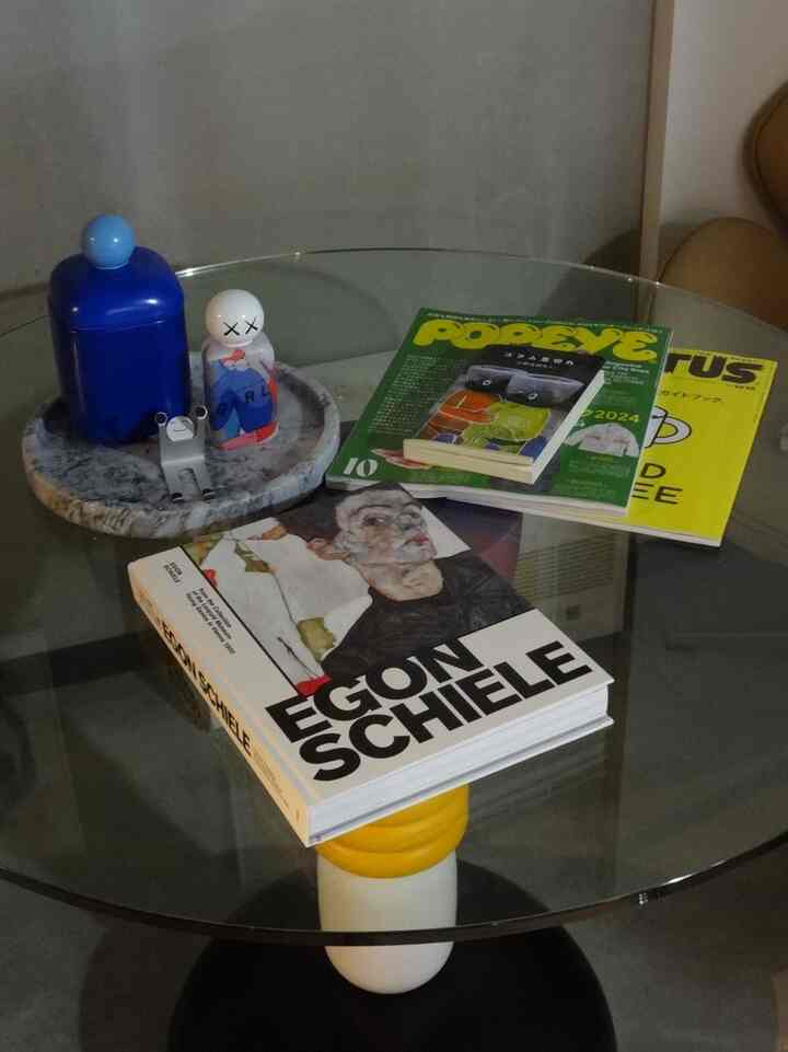 ガラステーブル上にアートブックと小物が置かれたミニマルな一人暮らしの空間