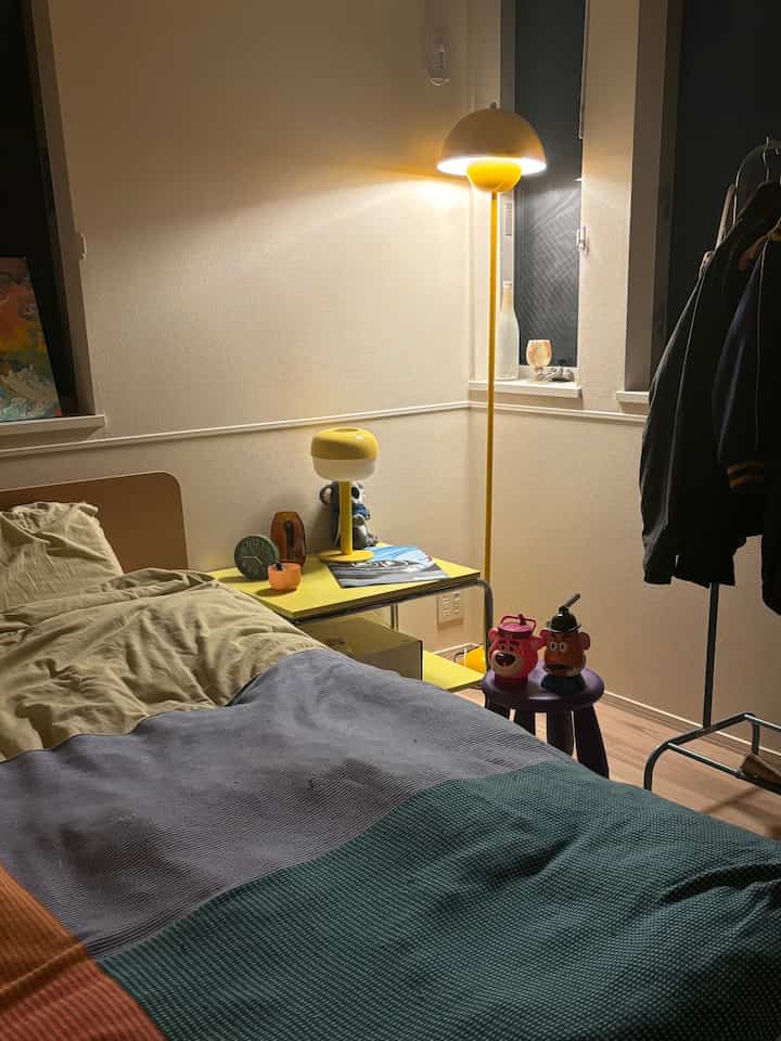 Cozy bedroom with warm yellow lighting and beige bedding, featuring white painted walls that create a soft atmosphere