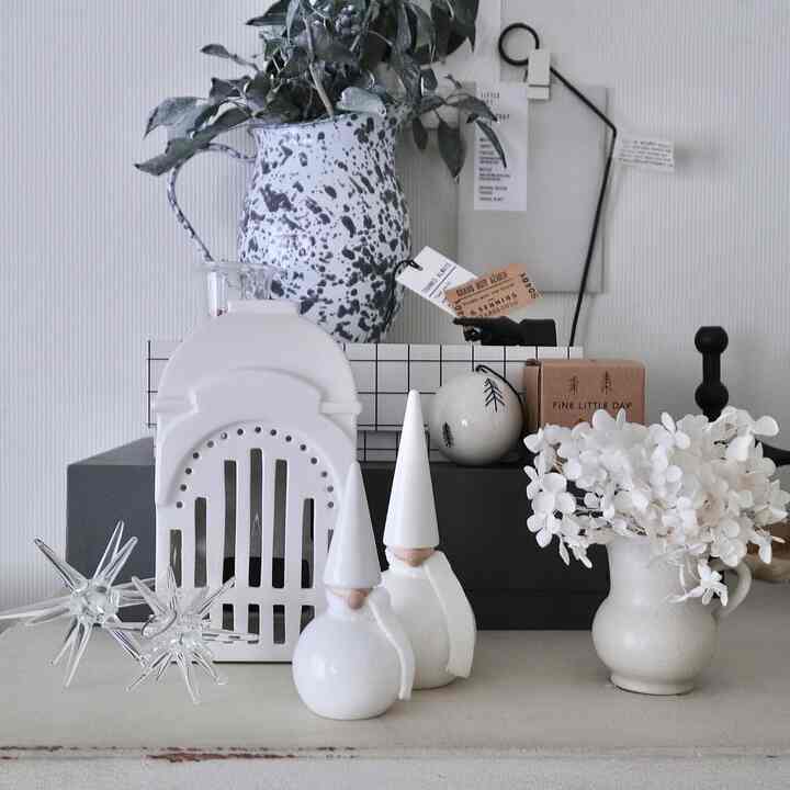 Natural and white toned table display featuring Christmas ornaments and a vase in a clean decorative setting