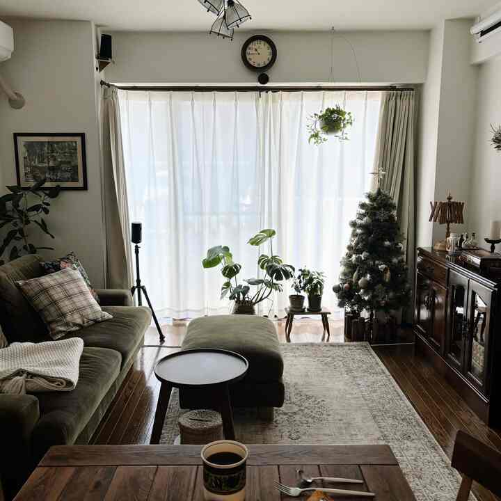 Natural and vintage brown toned living room featuring olive green sofa, Christmas tree, and plants with a warm atmosphere