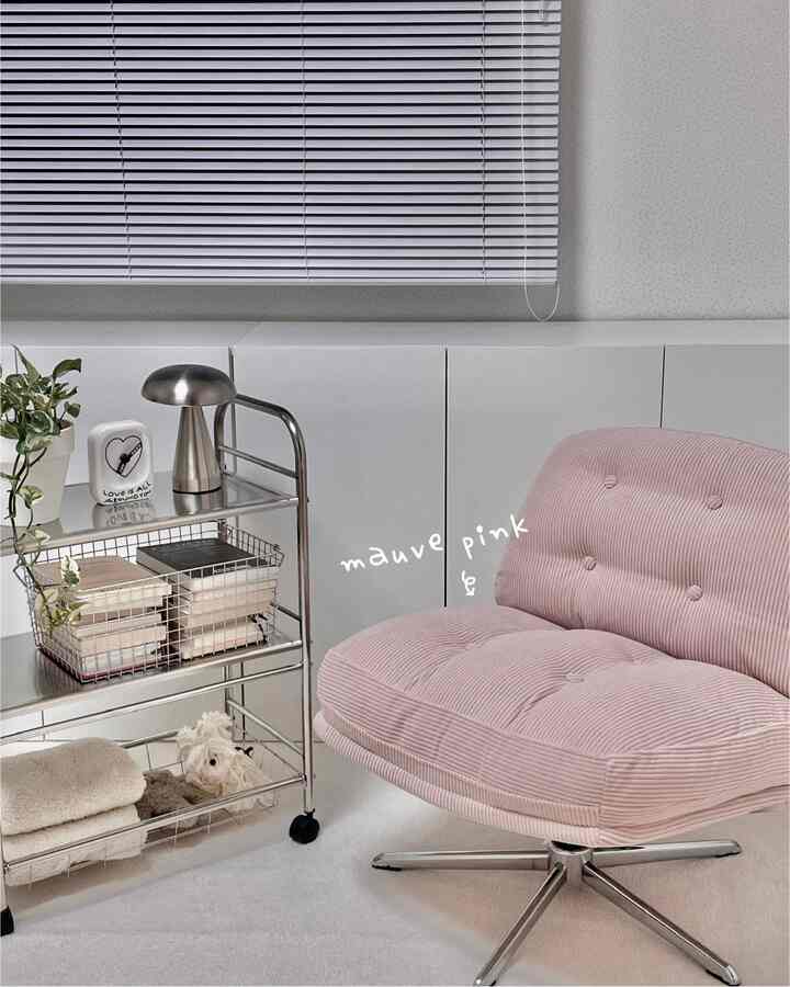 白とシルバーのメタルトーンが主調で、モーブピンクのアームチェアが際立つミニマルモダンなリビングスペース