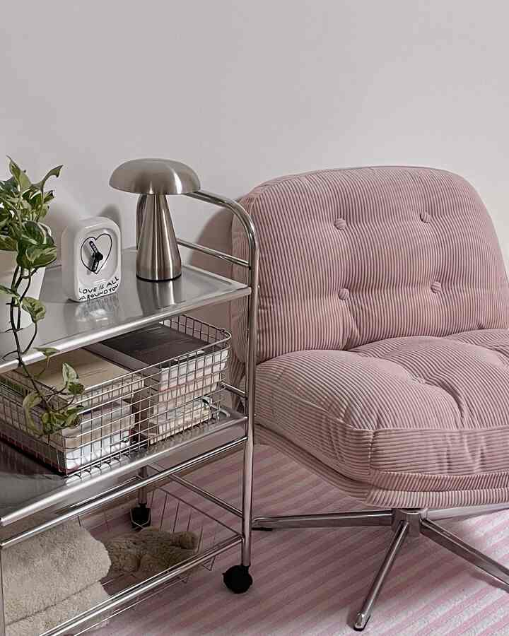 Modern living room featuring pink armchair and silver metal cart with striped pink rug