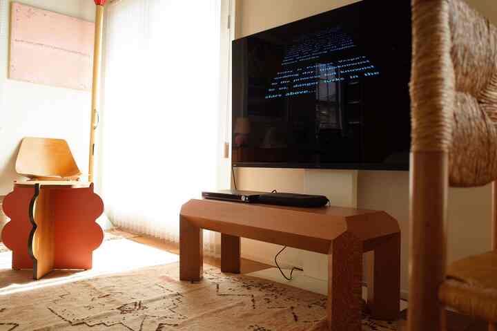 ブラウン調のリビング、個性的なコーヒーテーブルと壁掛けテレビが配置されたシンプルで自然な雰囲気のインテリア