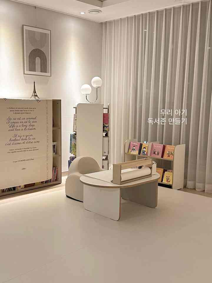 A simple modern living room featuring a baby reading zone with white and natural wood tones